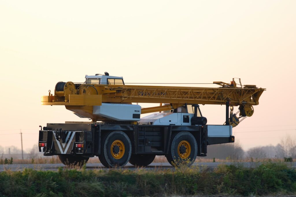 Heavy duty mobile lifting crane driving on intercity road at sunset