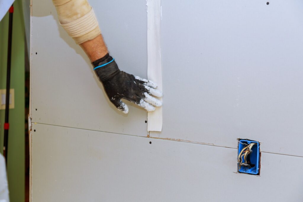 Man installing gypsum plasterboard construction with drywall installed